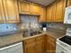 Kitchen featuring stainless steel sink, wooden cabinets, tile backsplash, and granite counters at 5511 N Ocean Blvd. # 1006, Myrtle Beach, SC 29577