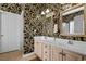 Bathroom with dual sinks, neutral countertops, decorative mirrors, and striking leaf-patterned wallpaper at 5719 Whistling Duck Dr., North Myrtle Beach, SC 29582