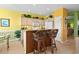 Charming kitchen with a breakfast bar, wicker stools, cream colored cabinets, and decorative accents, bathed in yellow and green hues at 5719 Whistling Duck Dr., North Myrtle Beach, SC 29582