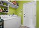 Well-organized laundry room with washer, dryer, storage shelves, and bright green walls at 5719 Whistling Duck Dr., North Myrtle Beach, SC 29582