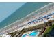 Aerial view of a crowded beach with colorful umbrellas, a swimming pool, and an ocean view at 5907 S Kings Hwy. # 1409, Myrtle Beach, SC 29575