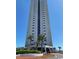 Exterior view of high-rise condo complex with palm trees and well-maintained landscaping under a clear blue sky at 5907 S Kings Hwy. # 1409, Myrtle Beach, SC 29575