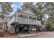 Stilt home shows covered parking beneath a large porch with fans, and gray and white siding at 6001-1723 South Kings Hwy., Myrtle Beach, SC 29575