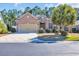 Single-story brick house featuring a two-car garage, well-manicured lawn, and mature trees, creating a welcoming curb appeal at 110 Summerlight Dr., Murrells Inlet, SC 29576