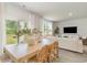 Bright dining area next to a living room, featuring a wooden table, wicker chairs, and natural light from large windows at 1434 Porchfield Dr., Conway, SC 29526