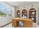 Bright office with a wooden desk, arched built-in shelving, and serene outdoor views at 1434 Porchfield Dr., Conway, SC 29526