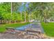 Shuffleboard court surrounded by lush landscaping and mature trees, with benches provided for resting at 2166 Marion Circle, Little River, SC 29566