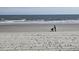 Scenic view of a sandy beach with ocean waves and a person with a stroller at 2204 S Perrin Dr. # 3, North Myrtle Beach, SC 29582