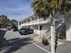 Exterior view of a multi-story condo or hotel, with a parking area and a tropical tree at 2204 S Perrin Dr. # 3, North Myrtle Beach, SC 29582