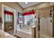 Bathroom featuring a tub, glass-enclosed shower, with transom window and red accent window treatments at 48 Heston Ct., Pawleys Island, SC 29585