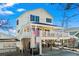 Inviting two-story yellow home with a covered porch, featuring an American flag and ground-level parking at 6001- 5411 S Kings Highway, Myrtle Beach, SC 29575