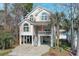 Inviting raised beach house featuring a spacious porch, neutral palette, complemented by lush landscaping and convenient parking below at 720 Melody Ln., Surfside Beach, SC 29575