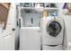 Bright laundry room with a stacked washer and dryer and ample shelving for storage and supplies at 920 Sewing Bee Pl., Little River, SC 29566