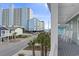 Balcony view showcasing a street with palm trees and condo buildings, with a partial view of the ocean at 119 Sunset Dr., Murrells Inlet, SC 29576