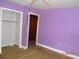 A bedroom with purple walls, showing the ceiling fan, closet, and hardwood floor at 12 E Sassafras St., Andrews, SC 29510