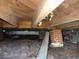 View of the crawlspace showcasing wooden beams, brick supports, and under-house utilities at 12 E Sassafras St., Andrews, SC 29510