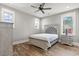 A well-lit bedroom with grey walls, wood floors, a ceiling fan and large windows at 128 Seabreeze Dr., Murrells Inlet, SC 29576