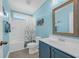 A bathroom featuring blue walls, a shower-tub combo, toilet, and a vanity with a sink and a framed mirror at 132 Summerlight Dr., Murrells Inlet, SC 29576