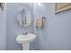 A charming powder room is decorated with light blue walls, a pedestal sink, round mirror, and a decorative painting at 132 Summerlight Dr., Murrells Inlet, SC 29576