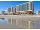 Stunning oceanfront condo building reflecting on the beach with clear blue skies at 1903 S Ocean Blvd. # 701, North Myrtle Beach, SC 29582