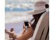 Personal in straw hat lounges on the beach using cell phone at 2307 S Ocean Blvd. # 5A, North Myrtle Beach, SC 29582