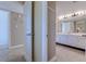 Hallway perspective featuring a bathroom with white cabinetry, a spacious countertop, and ample lighting at 2307 S Ocean Blvd. # 5A, North Myrtle Beach, SC 29582