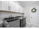 Functional laundry room with upper cabinets, appliances, and a door with a decorative wreath at 2409 Silkgrass Ln., Myrtle Beach, SC 29579