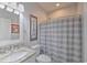 Well-lit bathroom with a granite countertop vanity, toilet, and a shower with a striped shower curtain at 377 Waties Dr., Murrells Inlet, SC 29576