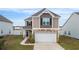 Front view of two-story home featuring stone accents, a two-car garage, and a well-maintained lawn at 5519 Redleaf Rose Dr., Myrtle Beach, SC 29579