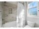 Bright bathroom with tiled shower and bathtub, featuring a tiered white shower curtain and window at 7624 Azure Dr., Myrtle Beach, SC 29572