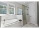 Bright bathroom featuring a standalone tub, glass shower, and marble tile at 7624 Azure Dr., Myrtle Beach, SC 29572