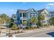 Charming two-story blue home featuring a double porch, palm trees, and lovely landscaping at 7624 Azure Dr., Myrtle Beach, SC 29572