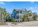 Eye-level view of a charming two-story blue home, framed by palm trees, set against a bright blue sky at 7624 Azure Dr., Myrtle Beach, SC 29572