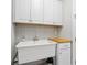 Functional laundry room featuring white cabinetry, a sink, and a patterned backsplash at 7624 Azure Dr., Myrtle Beach, SC 29572