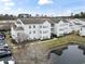 An aerial view of a condo community with pond, parking and manicured landscaping under a blue sky at 2276 Essex Dr. # Apt H, Surfside Beach, SC 29575