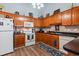 Kitchen boasts wood cabinets, black counters, white appliances, and tiled backsplash and flooring at 4239 Rivergate Ln., Little River, SC 29566