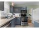 Well-lit kitchen with stainless steel appliances, gray cabinets, and tile flooring at 4908 Main St., Loris, SC 29569