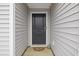 A close-up of the home's entrance reveals a solid door and gray siding with a welcome mat at 519 Grass Fern Ct., Longs, SC 29568