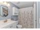 Well-lit bathroom featuring a white vanity, toilet, and shower with floral curtain at 6001-1086 S Kings Hwy., Myrtle Beach, SC 29575