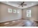 Bedroom with hardwood floors, a dark ceiling fan, and multiple windows providing views of the lush surroundings at 713 9Th Ave. S, North Myrtle Beach, SC 29582