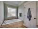 Jetted bathtub with tile surround, a privacy window, and a white paneled door at 1006 Clubhouse Dr., North Myrtle Beach, SC 29582