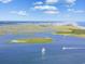 Aerial view of a scenic coastal landscape with waterways, marshes, beaches, boats, and bright blue sky with clouds at 1609 Seachase Way, North Myrtle Beach, SC 29582