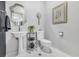 Well-lit half bathroom featuring a pedestal sink, decorative mirror, and a tiled floor at 1616 Hawthorn Dr., Pawleys Island, SC 29585