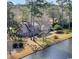 Waterfront home featuring mature trees, beautiful landscaping, and brick exterior at 1616 Hawthorn Dr., Pawleys Island, SC 29585