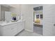 Bathroom with double sinks, a large mirror, and an adjoining bedroom with a tray ceiling at 1705 Seachase Way, North Myrtle Beach, SC 29582