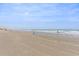 Expansive ocean view from sandy beach with people enjoying the surf and blue skies at 1903 S Ocean Blvd. # 606, North Myrtle Beach, SC 29582