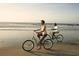 A couple enjoys a leisurely bike ride along the sandy beach with the ocean waves in the background at 280 Warner Crossing Way, Loris, SC 29569