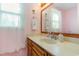 Bathroom vanity with wooden cabinets, a large mirror, and a window with sheer curtains at 317 14Th Ave. N, Surfside Beach, SC 29575