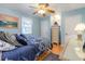 Comfortable bedroom featuring a blue bedspread and light blue walls, with a ceiling fan and wooden floors at 317 14Th Ave. N, Surfside Beach, SC 29575