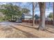 Exterior view of a blue two-story home with a gravel driveway and mature trees at 317 14Th Ave. N, Surfside Beach, SC 29575